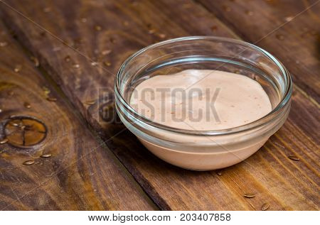 Sauce in a glass bowl on a background of a board