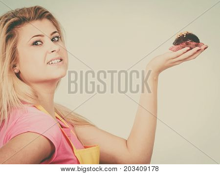 Diet sweets food concept. Woman holding delicious chocolate cupcake with peanut frosting about to take bite