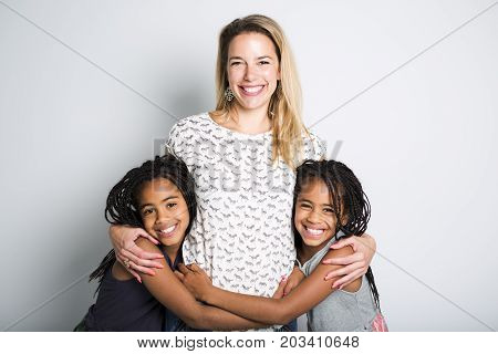 Two Afro twin child posing on a gray background studio with mother