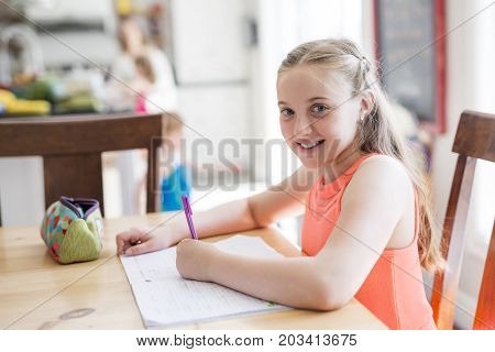 A cute teen girl doing homework at home
