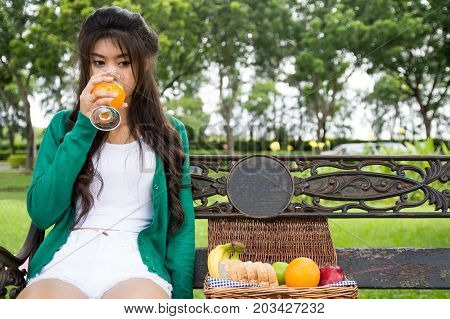 Young Woman Holding Glass Drinking Orange Juice With Friuits Basket. Top View From Back. Healthy Con