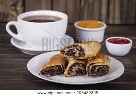 Crepes stuffed with poppy seeds nuts and honey on white plate for breakfast. Delicious pancakes wrapped with poppy seeds