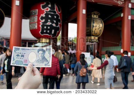 Tokyo Japan - April 23 2017 : Touris hold 1000 japanese yen banknote with Kaminarimon gate at Asakusa shrine background