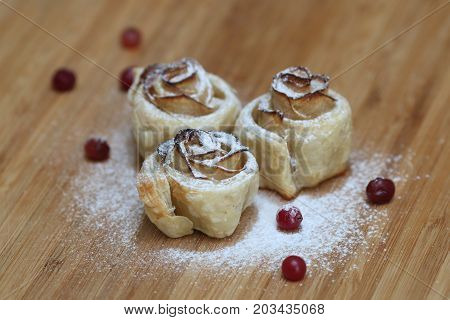 Strudel with apples and cranberries. bun with apples and cranberries sprinkled with powdered sugar on wood background. Variation apple strudel summer pie. Summer breakfast.