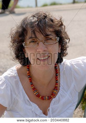 a portrait of a middle-aged brunette woman with eyeglasses outdoor
