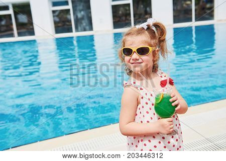Cute little blonde at the pool and holding achild's cocktail .