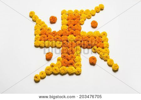 stock photo of hindu auspicious symbol called Swastika made using marigold flower or zendu or genda phool, Flower rangoli in the shape of Swastika for diwali/pongal/onam over white background