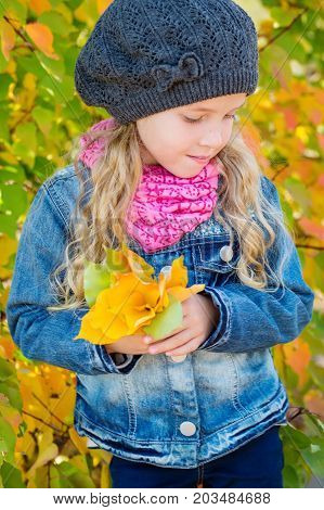 adorable little girl with autumn leaves in thepark on a walk