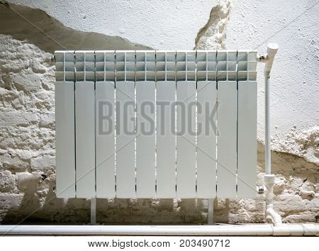 Bimetallic radiator near the wall with crumbling plaster