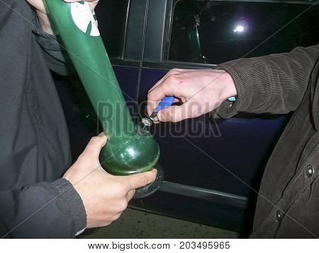 Ignition Of Cigarette Lighter In A Bong. Bong Smoking. Smoking Through The Bong Is Marijuana.