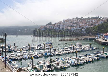 Boats In A Port In Lastres With The Village Behind, Asturias, Spain