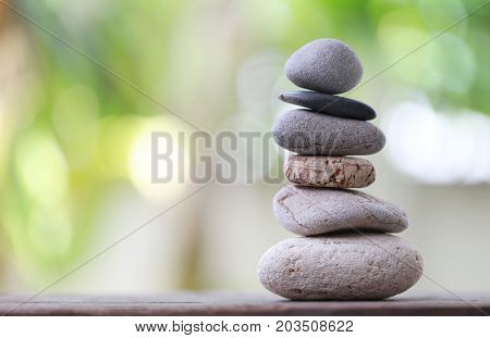 Balance Stones stacked to pyramid in the soft green background to Spa ideas design or freedom and stability concept on rocks.