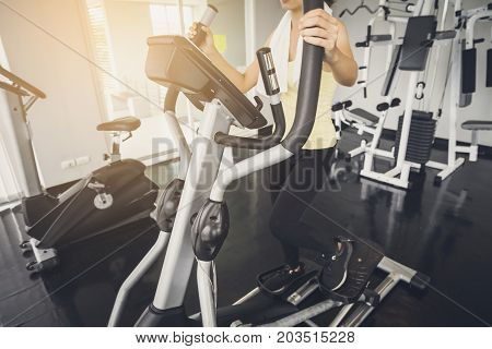 Young asian woman exercising on the xtrainer machines in gym