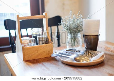 Beautiful houseplant in flowerpot tissue in black box garnish (pepper toothpick sauce) in wooden box and spoon/fork set on wooden table and black chair for food background - interiors concept.