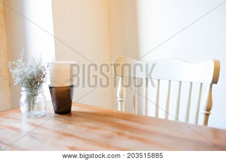 The beautiful houseplant with clear flowerpot and tissue in black box set on brown wooden table and white chair for food or home background or texture - interiors concept.