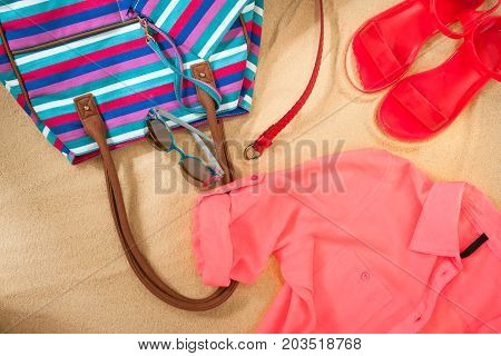 set of bright summer clothes for the beach on the golden sand