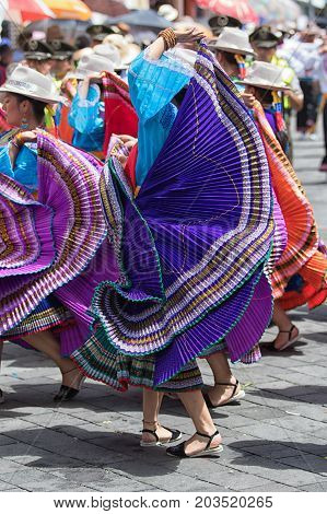 June 17 2017 Pujili Ecuador: female dancer in bright color traditional wear performing on the street at Corpus Christi celebrations