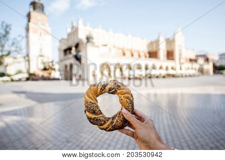 Holding prezel, traditional polish snack on the Market square in Krakow