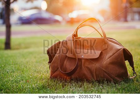 Retro brown shoes and man leather bag in bright colorful summer grass in the park.