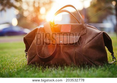 Retro brown shoes and man leather bag in bright colorful summer grass in the park.