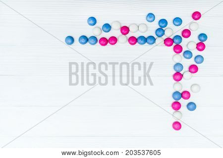 Frame from colorful mint coated candies texture on white wooden background. Top view. Copy space