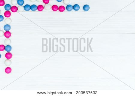 Frame from colorful mint coated candies texture on white wooden background. Top view. Copy space