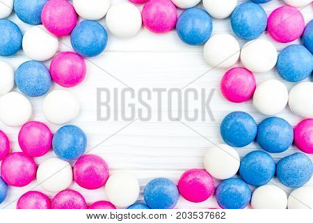 Frame from colorful mint coated candies texture on white wooden background. Top view. Copy space