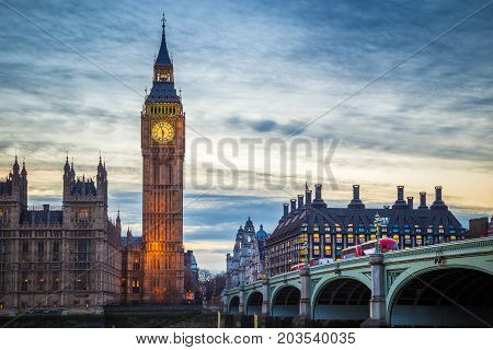 London England - The famous Big Ben and Houses of Parliament with iconic red double decker buses on Westminster Bridge at dusk