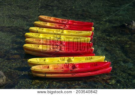Colorful canoes on water. Red and yellow kayaks ready for summer activities and recreation.