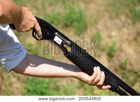 Man holds a shotgun at the shooting field