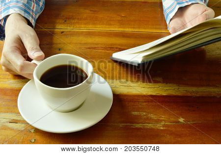 hand open book and read while drinking black coffee