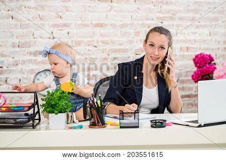 Family Business - telecommute Businesswoman and mother with kid is making a phone call. At the workplace, together with a small child