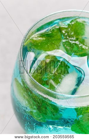 Trendy blue moscato wine in a glass served with mint ice cubes vertical closeup