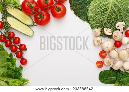 Border of fresh organic vegetables, fruits and nuts on white background. Healthy natural food on table with copy space. Cooking ingredients top view, mockup for recipe or menu