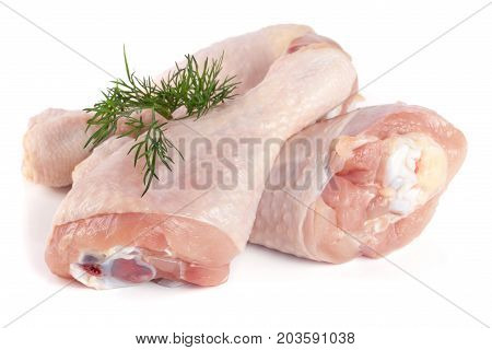 Three raw chicken drumsticks with a sprig of dill isolated on white background.