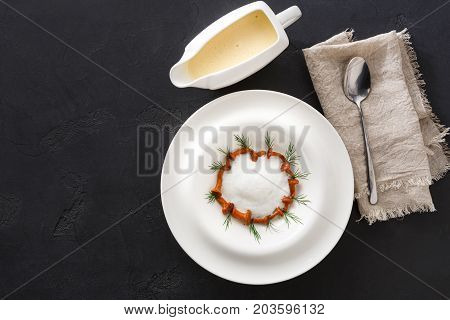 Delicious cream soup with honey fungus top view, copy space. Gourmet meal with mushrooms and jug of broth, restaurant serving