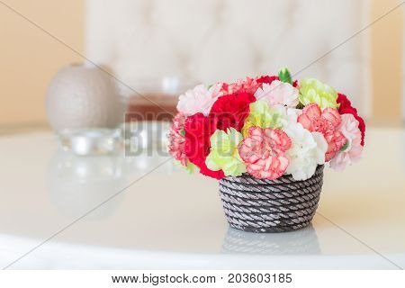 Colorful Carnations In Brown Vase And Candle On Marble Table.