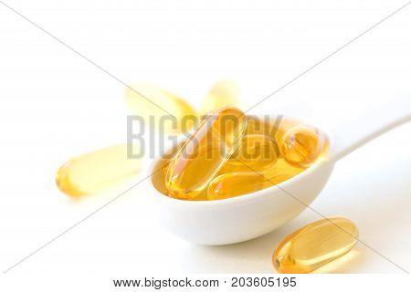 Fish oil capsules in a spoons on white background.