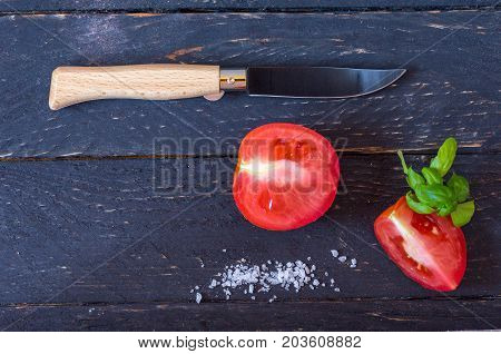 Knife With A Wooden Handle And A Black Blade. Sliced Red Tomatoes On A Black Background.