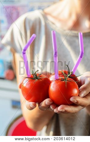 Three Ripe Red Tomatoes with Straws in Woman Hands on Bright Background. Fresh Juice Healthy Food Concept. Tomato as a Vessel with Fresh Juice