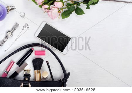 Flowers perfume watch bracelet mobile phone handbag cosmetics on a white wooden background