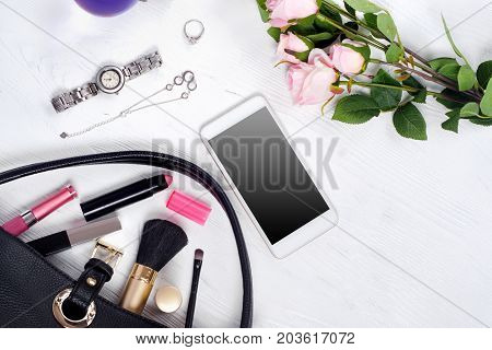 Flowers perfume watch bracelet mobile phone handbag cosmetics on a white wooden background