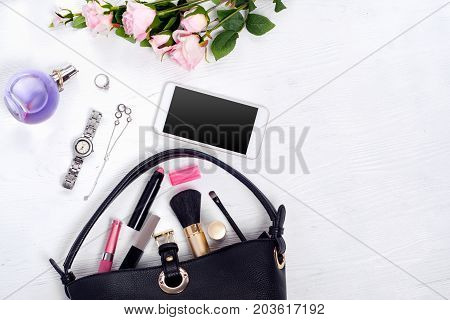 Flowers perfume watch bracelet mobile phone handbag cosmetics on a white wooden background