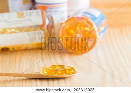 Fish Oil Omega 3 With Vitamin D Capsules Good For Heart Health In Spoon And Bottle On A Wooden Backg