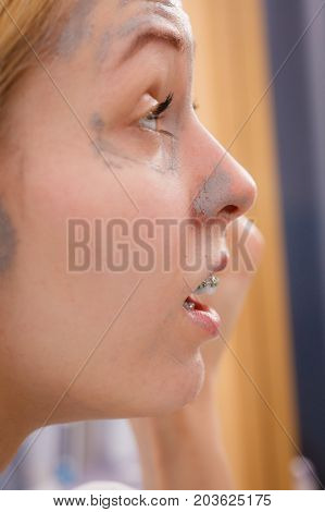 Woman Removing Mud Facial Mask With Sponge