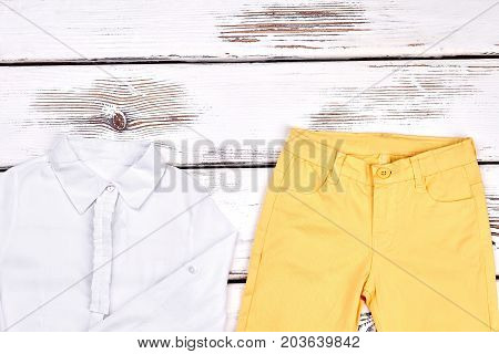 Teenage girls elegant outfit. Young girl white blouse and skinny colored trousers on white wooden background. Girls classic outfit.
