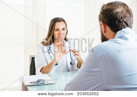 Female doctor is showing an aerosol inhaler to a man at her office