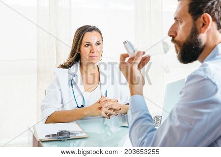Male patient is inhaling a medicament from an aerosol inhaler placed on a space chamber at her office