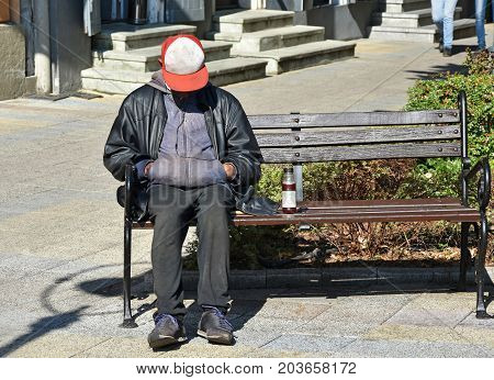 Homeless man sleeps on a bench in the city