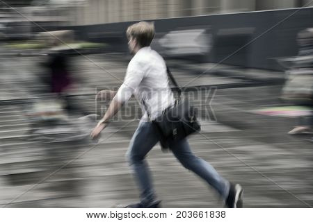 Young man in a hurry. Blurred ation on urban square after rain.